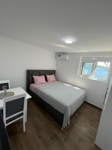 a bedroom with a bed with pink pillows and a table at Azzure Apartment in Ulcinj