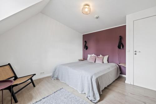 a bedroom with a white bed and a purple accent wall at Downtown Baldursbrá Holiday Home in Reykjavík