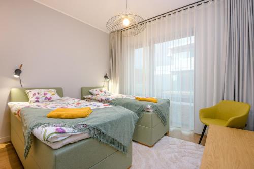 - une chambre avec 2 lits jumeaux et une chaise jaune dans l'établissement Bremeni Apartment Pärnu jõe kaldal, à Pärnu
