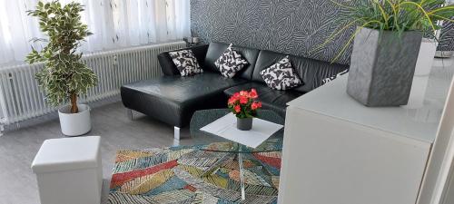 a living room with a black leather couch and plants at Ferienwohnung 90 m2 in Sulzbach 2 Minuten Fußweg zum Krankenhaus in Sulzbach
