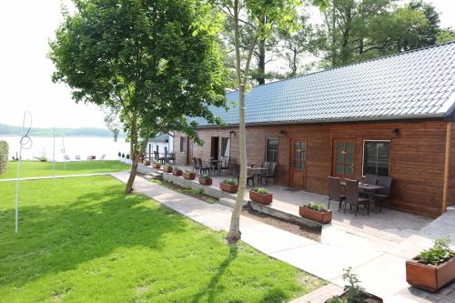 a wooden cabin with tables and chairs in a yard at Seeblick Apartment am Mellensee in Mellensee
