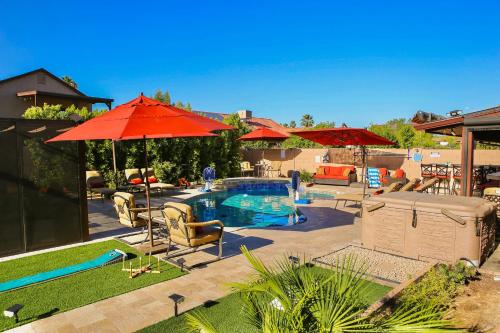 a backyard with a pool with red umbrellas and chairs at Family Home Vacation Retreat Glendale AZ in Phoenix