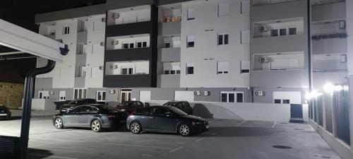 three cars parked in a parking lot in front of a building at In Dream Apartman in Inđija