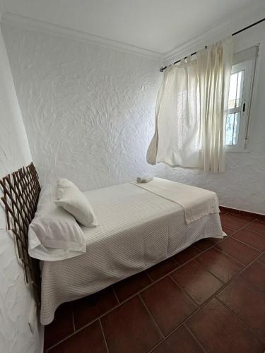 a bedroom with a bed with a window and white sheets at Dúplex Centro Histórico Tarifa in Tarifa