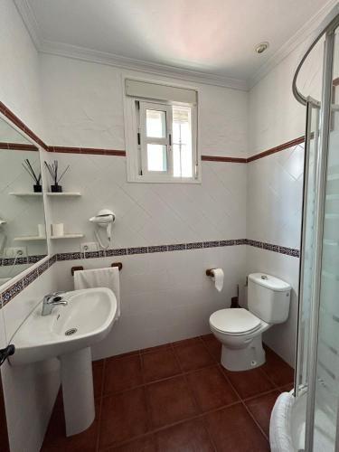 a white bathroom with a sink and a toilet at Dúplex Centro Histórico Tarifa in Tarifa