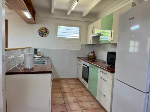 a kitchen with white cabinets and a white refrigerator at La Belle Epoque (3*) - Maison avec vue sur mer à Bouillante in Bouillante