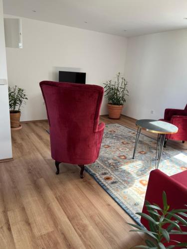 uma sala de estar com uma cadeira vermelha e uma mesa em Seeblick Apartment am Mellensee em Mellensee
