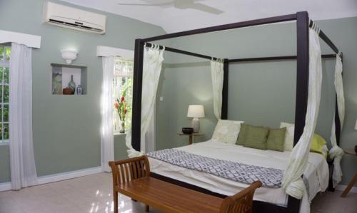 a bedroom with a canopy bed and a wooden table at Rafeen villa- Historic villa with pool in Bridgetown