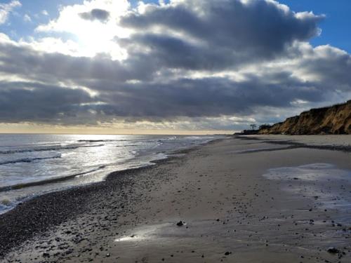a beach with a cloudy sky and the ocean at Pea Cottage Dog friendly and 5 mins to beach in Kessingland