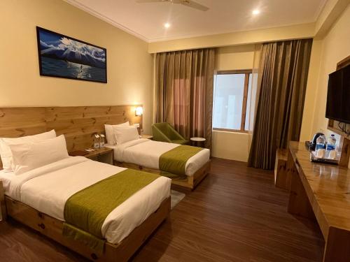a hotel room with two beds and a television at Crown Himalaya in Leh