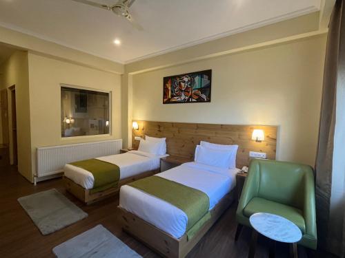a hotel room with two beds and a green chair at Crown Himalaya in Leh