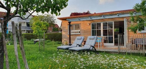 2 chaises assises sur la terrasse couverte d'une maison dans l'établissement Haus mit stilvoller Ferienwohnung und Tiny House nahe Ammersee für 2-6 Personen, à Geltendorf