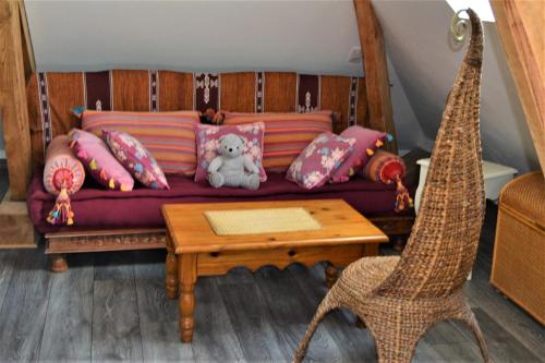 a couch with pillows and a teddy bear on it at Au temps suspendu in Champagney