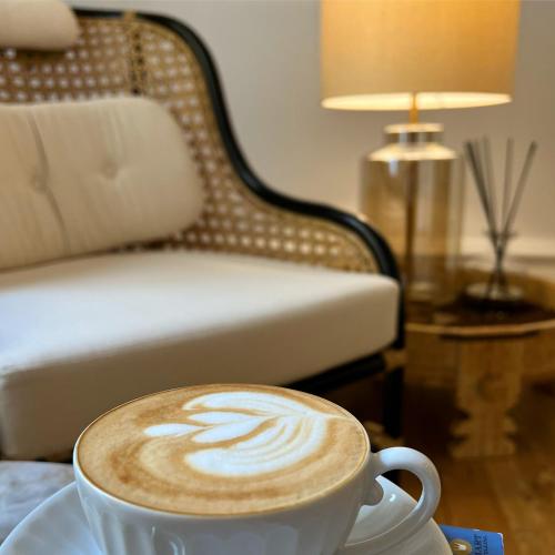 a cup of coffee sitting on a table next to a bed at Palácio do Visconde - The Coffee Experience in Lisbon