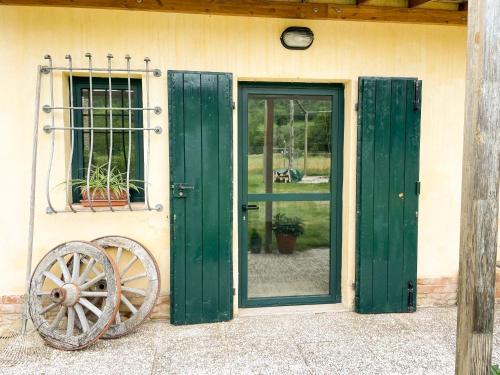 a building with green doors and a wheel next to it at Casale Al Fiume in Grottazzolina