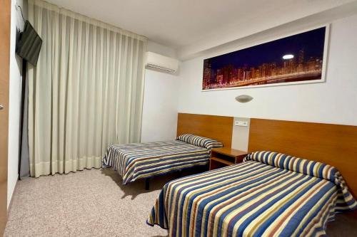 a hotel room with two beds and a tv at Pension La Orozca in Benidorm