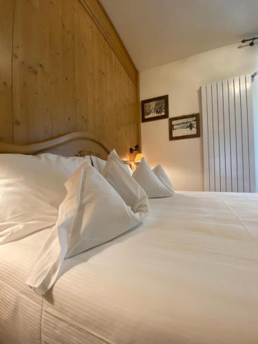 a white bed with white pillows in a bedroom at Albergo Rutzer in Asiago