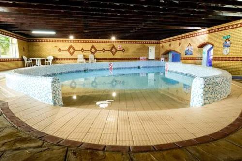 a large swimming pool in a large room with at Coghurst Hall themed static caravan in Westfield