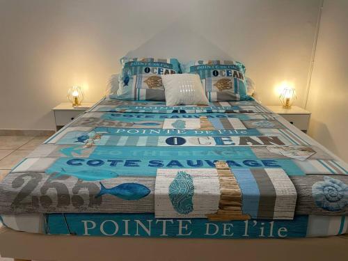 a large bed with a blue comforter on it at La Caïmite - Appartement convivial in Schœlcher