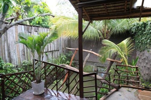 a garden with a wooden fence and palm trees at Vamxang Rustic Home in Can Tho