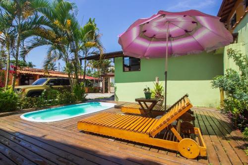 un patio con mesa, sombrilla y piscina en Suítes cambucá en Parati