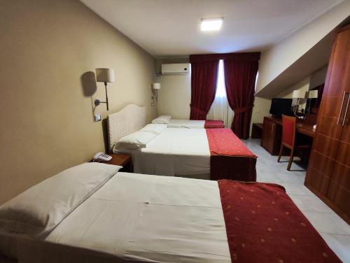 Habitación de hotel con 2 camas y escritorio en Pisani Hotel, en San Nicola La Strada