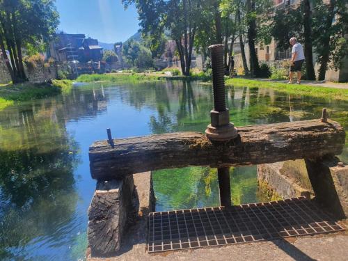 a wooden bench sitting next to a body of water at La ruelle des 2 vallées in Arreau