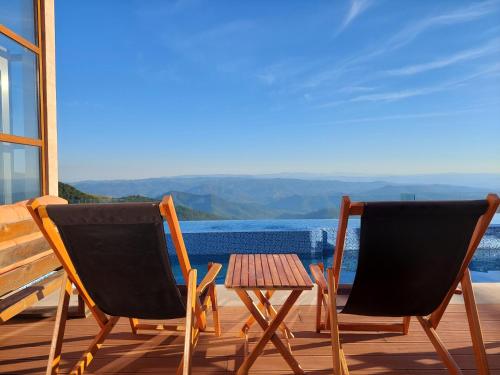 two chairs and a table on a deck with a view at Sunset View Ski & Spa apartments Kopaonik in Kopaonik