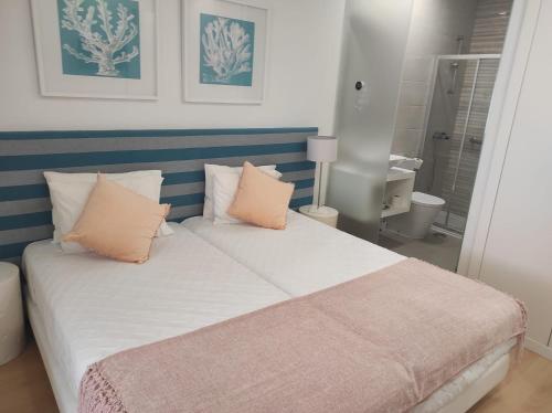 - une chambre avec un grand lit et des oreillers roses dans l'établissement By the Sea, à Nazaré