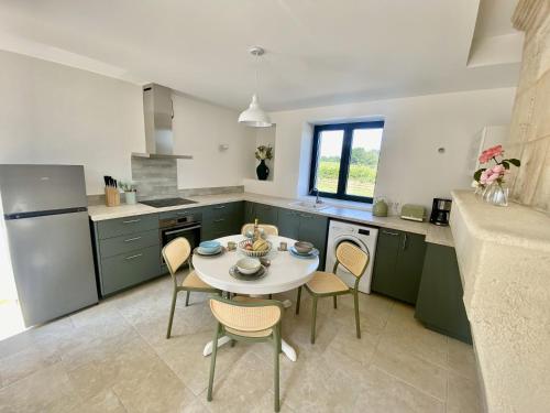 een keuken met groene kasten en een tafel en stoelen bij L'Eperonnette, cozy house with swimming pool, surrounded by vineyard, near St Emilion in Vérac