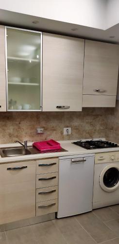 a kitchen with white cabinets and a sink and a washing machine at Caravel Appartamentini in Lido di Camaiore