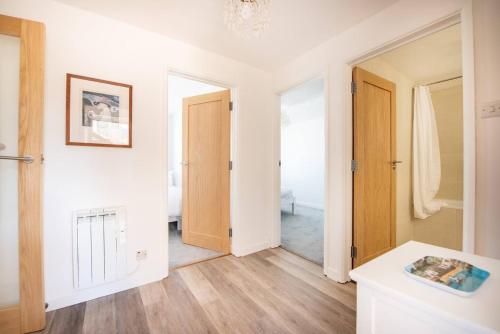 um quarto com paredes brancas, pisos em madeira e uma porta em Quiet family-friendly apartment 250 metres from beach and town em Newquay