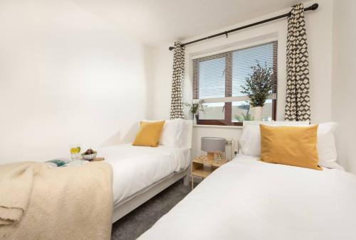 Duas camas brancas num quarto com uma janela em Quiet family-friendly apartment 250 metres from beach and town em Newquay