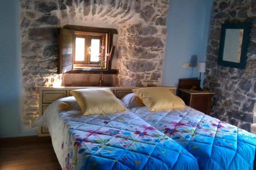 1 dormitorio con cama y pared de piedra en La Casona de Candamín, en Candamin