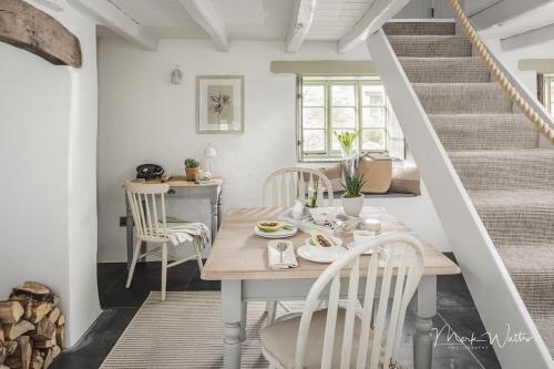 ein Esszimmer mit einem Tisch, Stühlen und einer Treppe in der Unterkunft Lillyville at Higher Treyone in Looe