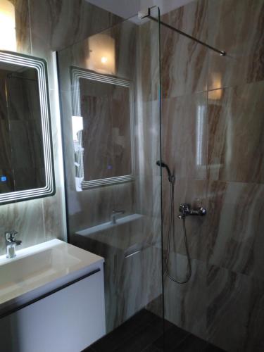 a bathroom with a glass shower and a sink at Studios Spiros Parga in Parga