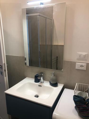 La salle de bains est pourvue d'un lavabo blanc et d'un miroir. dans l'établissement Leonardo luxury apartment, à Florence