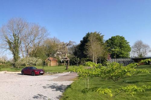 a red car parked in a gravel driveway at Hide on the Hill Cottage in Wells