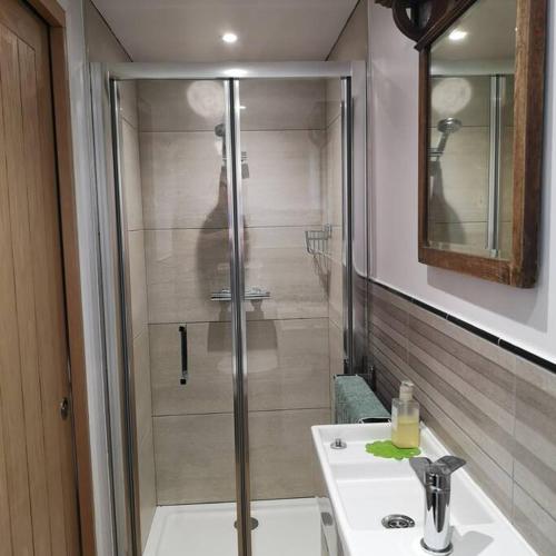 a bathroom with a shower and a sink and a sink at Hide on the Hill Cottage in Wells
