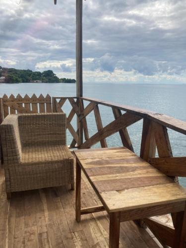 a wooden deck with a table and a chair at Soul Rebel Lodge & Backpackers in Nkhata Bay