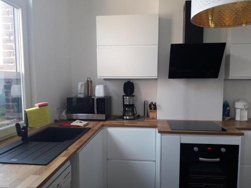 a kitchen with white cabinets and a sink and a microwave at Veronique schouckens in Binche