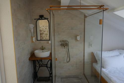 a bathroom with a shower and a sink next to a bed at Hotel Restoran Humsko in Trebinje