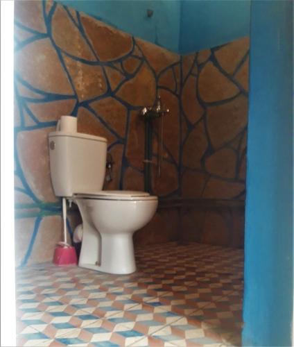 a bathroom with a toilet with a mosaic wall at Dounia Hostel in Tinerhir