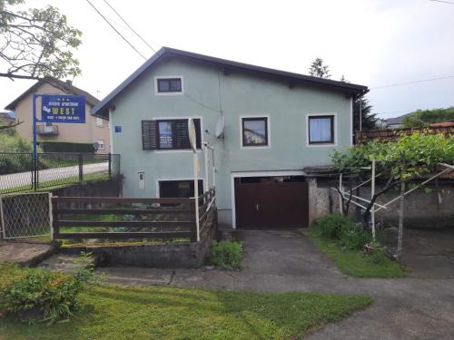 a white house with a gate in front of it at Studio apartman West in Ogulin