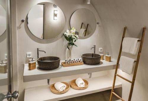 a bathroom with two sinks and two mirrors at Oia Mare Villas in Oia