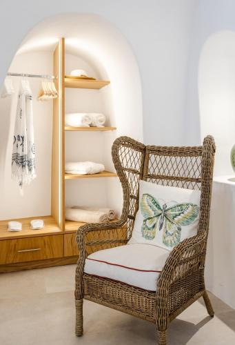 a wicker chair with a butterfly pillow in a room at Oia Mare Villas in Oia