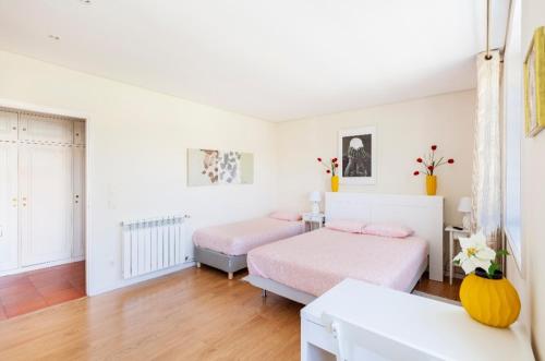 two beds in a bedroom with white walls and wood floors at Suites Foz O Porto in Porto