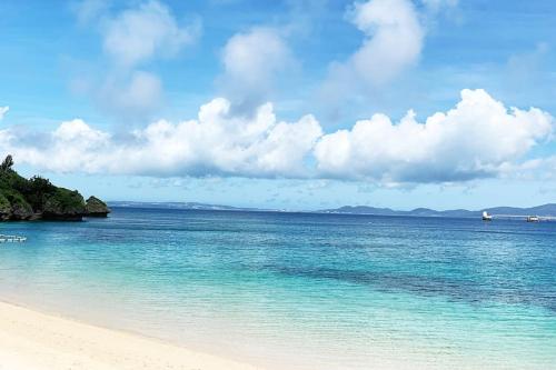 a beach with turquoise water and a cloudy sky at Kafuya miyagi in Ikemi