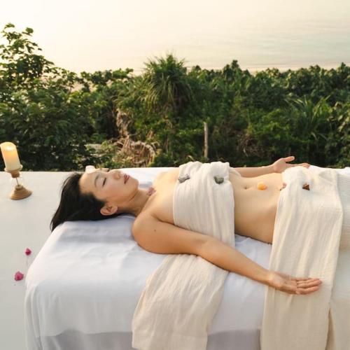 a woman laying on a bed with towels at Kafuya miyagi in Ikemi