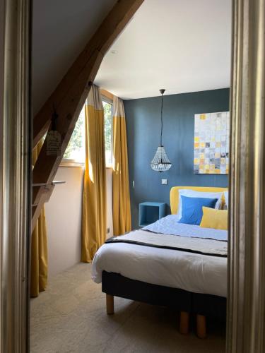 a bedroom with a bed with blue walls and yellow curtains at La Bastide de Barbizon in Barbizon